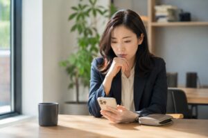 밝은 실내 테이블에 앉아 휴대폰을 보며 IRP 해지를 고민하는 30대 여성