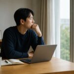 집에서 노트북을 앞에 두고 창밖을 바라보며 IRP와 S&P500 투자 방법을 고민하는 남성